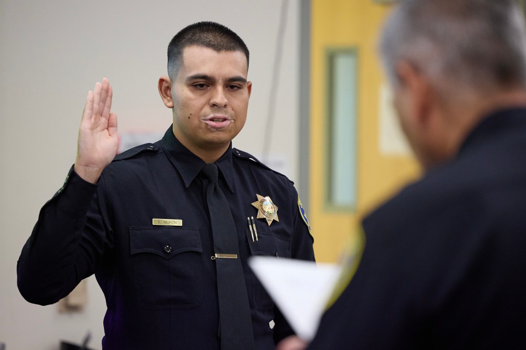 UC Davis Police officer Ernesto Moron repeats the oath as it is read to him by chief Joe Farrow at his swearing-in ceremony at the UC Davis Police department on Dec. 22, 2023. Photo by Fred Greaves for CalMatters